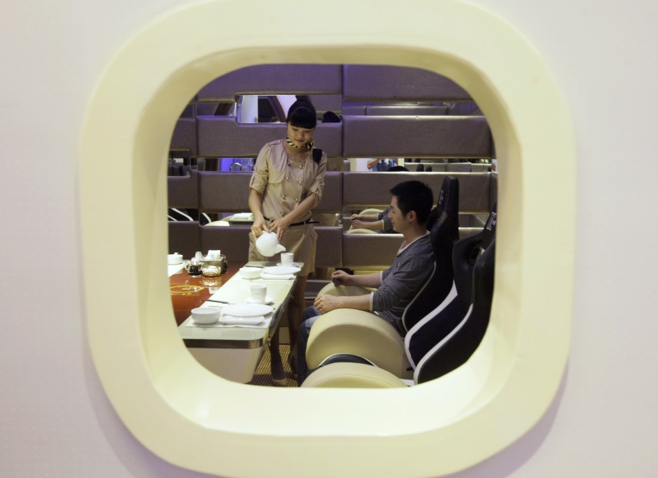 A waitress is framed within a window as she poses serving a customer at an A380 theme restaurant during a media event before its offical opening in Chongqing municipality