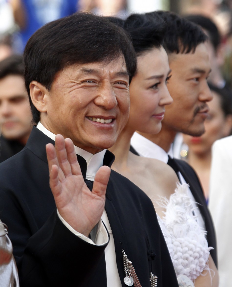 Actor Chan waves as he arrives on the red carpet with unidentified guests for the screening of the film De rouille et dos at the 65th Cannes Film Festival