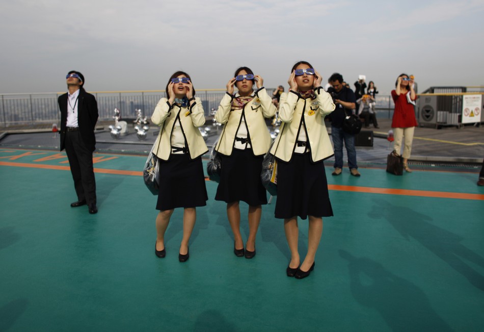 Bus tour guides look at an annular eclipse at a rooftop of the Roppongi Hills complex in Tokyo