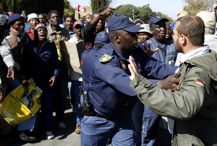 A police officer stops a member of the Afrikaner Resistance Movement (AWB) from approaching supporters of Mahlangu and Ndlovu (Reuters)