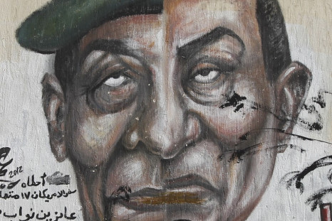 Egyptian man walks in front of a wall sprayed with graffiti depicting the faces of former President Mubarak and Field Marshal Tantawi in Cairo