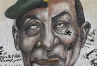 Egyptian man walks past graffiti depicting the faces of former President Mubarak and Field Marshal Tantawi in Cairo