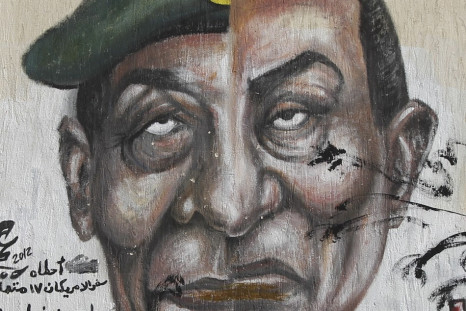Egyptian man walks past graffiti depicting the faces of former President Mubarak and Field Marshal Tantawi in Cairo