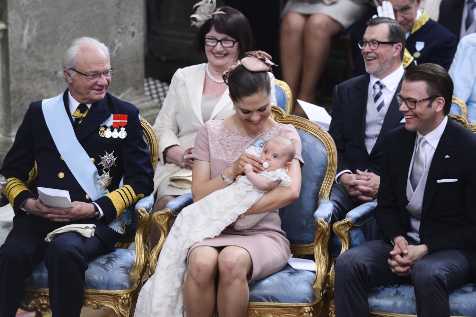Swedens King Carl XVI Gustaf, Crown Princess Victoria holding Princess Estelle and Prince Daniel and in the background his parents Ewa Westling and Olle Westling smile during a christening ceremony in Stockholm