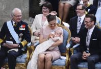 Sweden's King Carl XVI Gustaf, Crown Princess Victoria holding Princess Estelle and Prince Daniel and in the background his parents Ewa Westling and Olle Westling smile during a christening ceremony in Stockholm