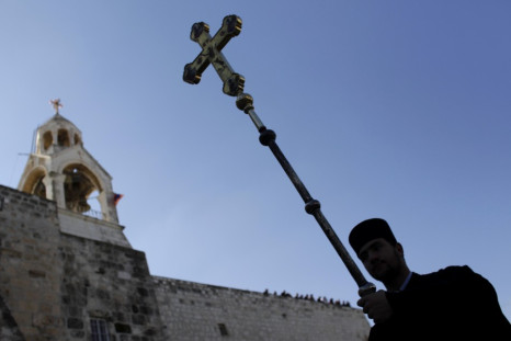 Greek Orthodox priest carries cross beside Church of the Nativity in Bethlehem