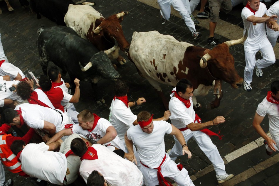 Runners sprint alongside Dolores Aguirre fighting bulls on Santo Domingo hill during the first running of the bulls of the San Fermin festival in Pamplona