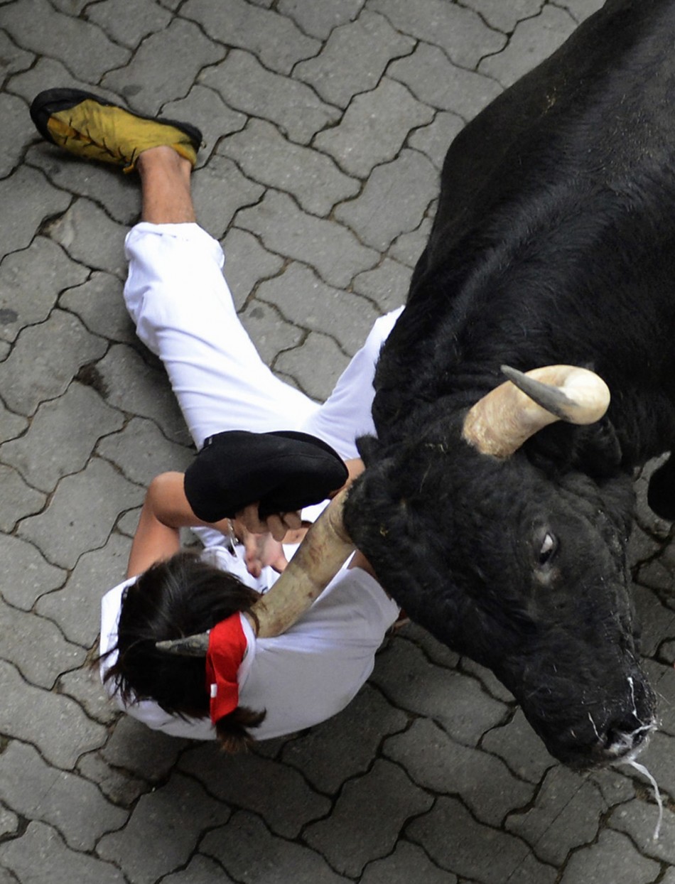 A runner is dragged by his scarf by a Dolores Aguirre fighting bull at the entrance to the bullring during the first running of the bulls of the San Fermin festival in Pamplona