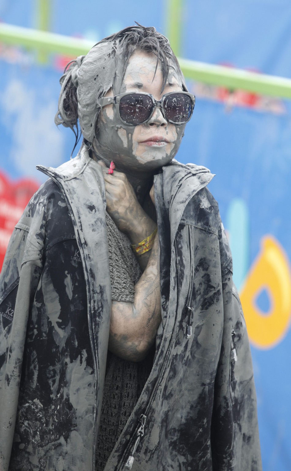 A woman wears a jacket to warm herself during the Boryeong Mud Festival at Daecheon beach in Boryeong