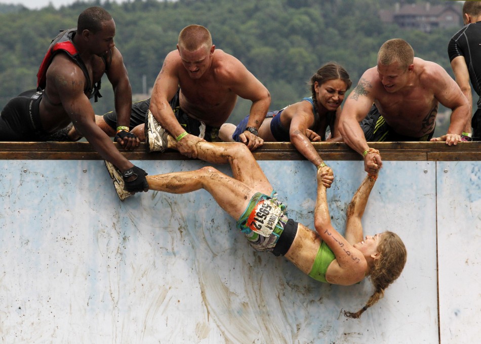 Competitors work to pull a woman up an obstacle where competitors must jump to the top of a half pipe during the Tough Mudder at Mt. Snow in West Dover
