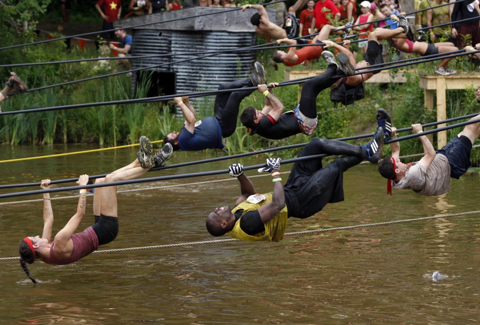 Competitors pull themselves over water along a rope during the Tough Mudder at Mt. Snow in West Dover