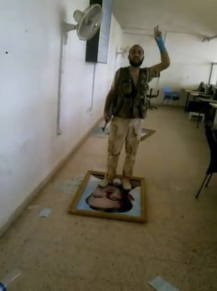 Rebel standing on photo of president on Iraq border