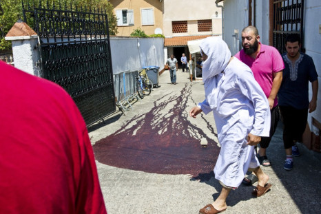 Islamic faithful walk past the blood-stained pavement outside the entrance of the Es Salam mosque following afternoon prayers in Montauban