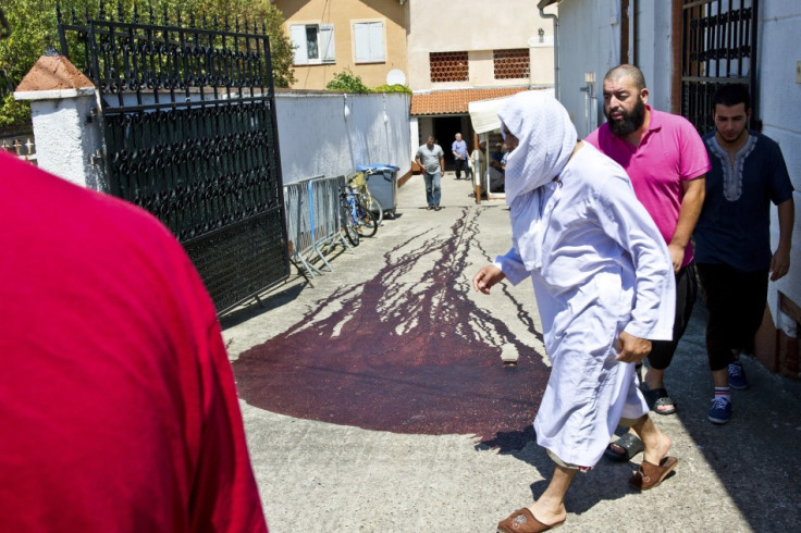 Islamic faithful walk past the blood-stained pavement outside the entrance of the Es Salam mosque following afternoon prayers in Montauban