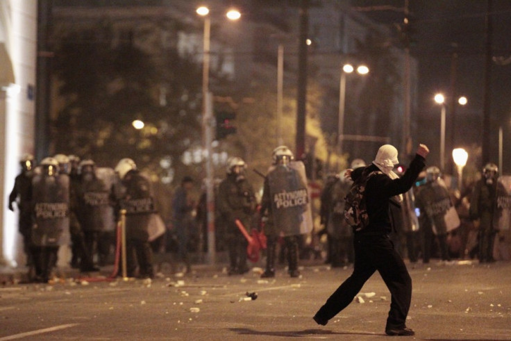 (Photo: A protester throws a stone at policemen during riots at central Syntagma square in Athens)