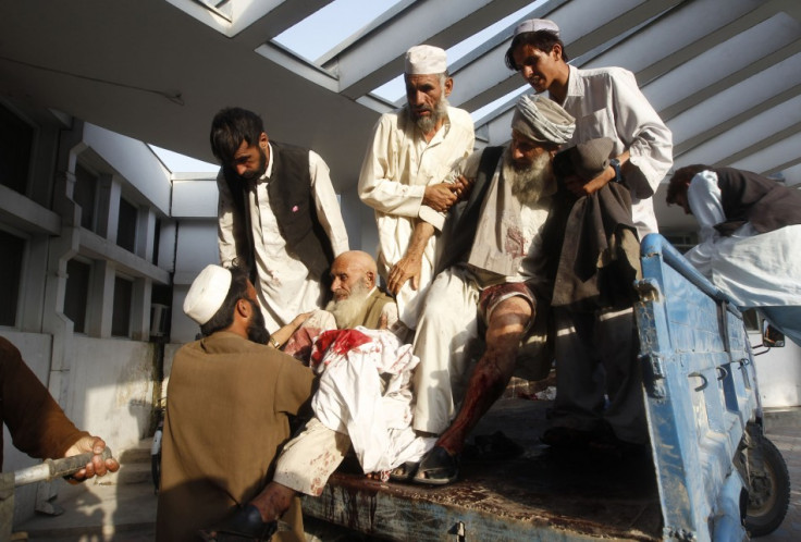 Afghan men assist those injured in a bomb blast as they arrive at a hospital in Jalalabad