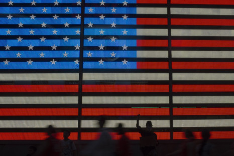 An Occupy Wall Street movement activist raises his fist while protesting in front of a digital flag of the United States