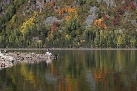 Local residents sit on a bank of the Yenisei River surrounded by reflection of the Siberian taiga in autumn foliage south of the city of Krasnoyarsk, September 13, 2012.  The first day of autumn arrived across the northern hemisphere with autumnal equinox