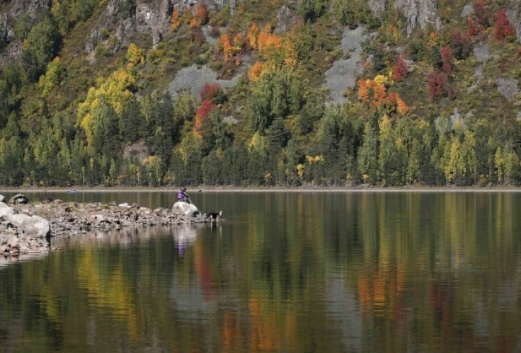 Local residents sit on a bank of the Yenisei River surrounded by reflection of the Siberian taiga in autumn foliage south of the city of Krasnoyarsk, September 13, 2012.  The first day of autumn arrived across the northern hemisphere with autumnal equinox