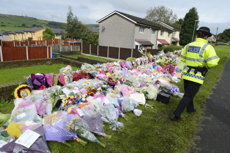An officer stands by floral tributes near the scene where two female police officers were shot, in Hattersley near Manchester