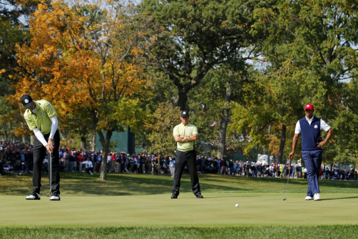 Team Europe's Colsaerts sinks a par putt in front of team-mate Westwood and Team USA's Woods