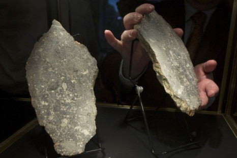 David Herskowitz, a Natural History Consultant at Heritage Auctions, handles a portion of Dar Al Gani 1058, the fourth largest piece of moon rock available to the public in New York October 12, 2012. The pieces of the rock, which are one rock split in two