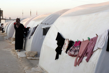 A Syrian refugee hangs her washings on a tent at a refugee camp on the outskirts of Azaz town
