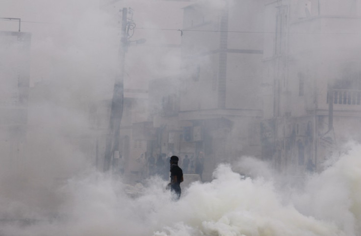 An anti-government protester walks through tear gas during clashes with riot police in the village of Mameer
