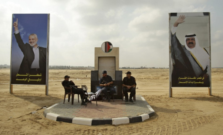 Members of Hamas security forces sit between posters depicting senior Hamas leader Haniyeh and Qatar's Emir Sheik Hamad