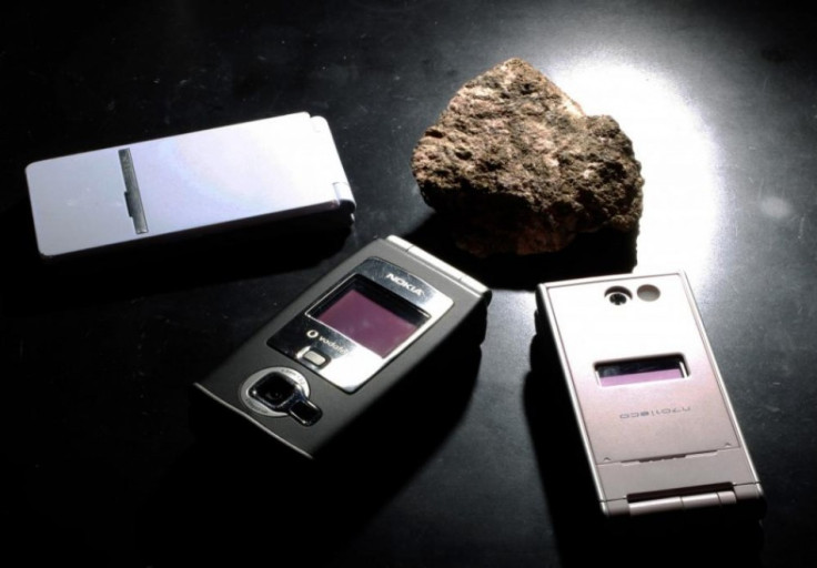 A bastnaesite mineral containing rare earth is pictured next to cell phones, which utilises the minerals during manufacturing at a laboratory (PHOTO: REUTERS)