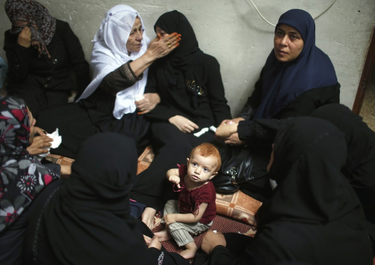 The daughter of a Hamas gunman sits near her crying mother during funeral in northern Gaza