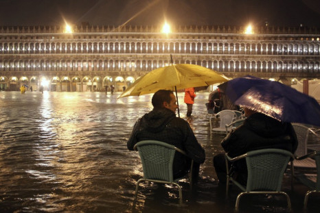 People walk in a flooded street during a period of seasonal high water in Venice
