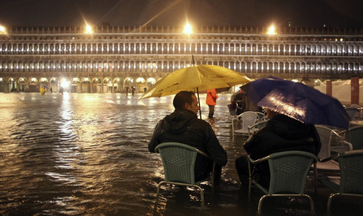 People walk in a flooded street during a period of seasonal high water in Venice