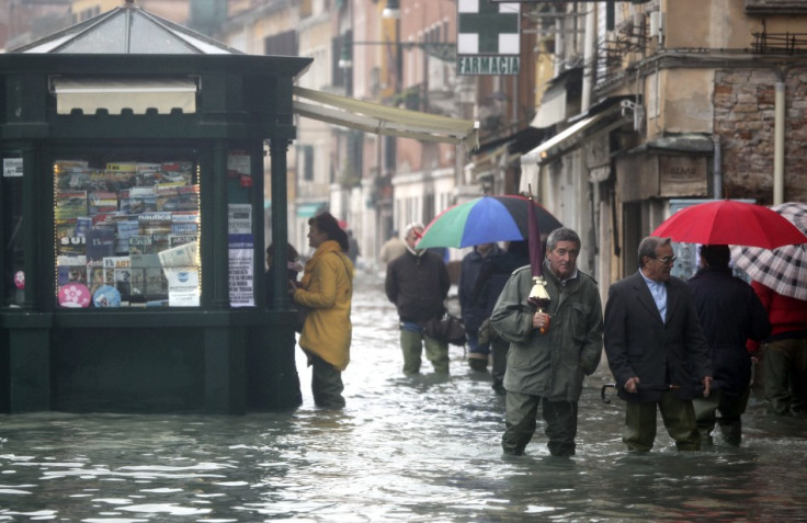 People walk in a flooded street during a period of seasonal high water in Venice