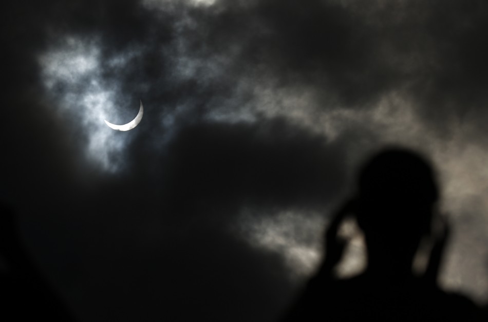 Tourist watches as the moon passing in front of the sun as it approaches a full solar eclipse in the northern Australian city of Cairns