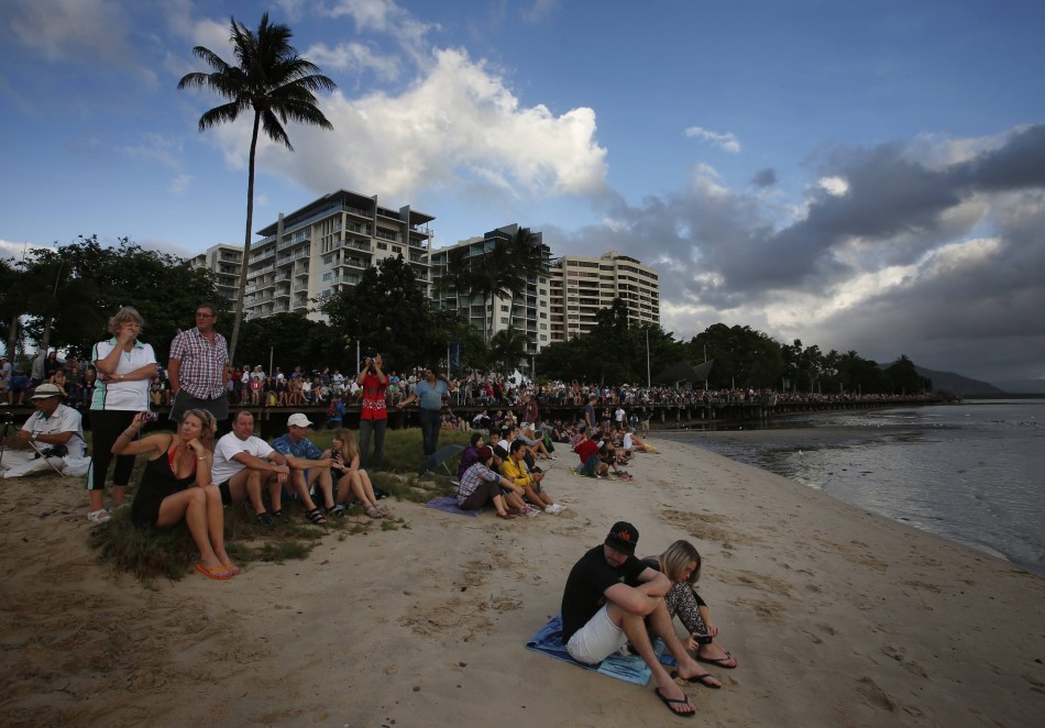 Tourists look at a cloudy sky as a full solar eclipse begins in the northern Australian city of Cairns