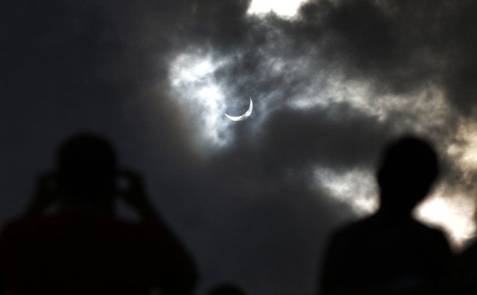 Tourists watch as the moon blocks the sun as it approaches a full solar eclipse in the northern Australian city of Cairns
