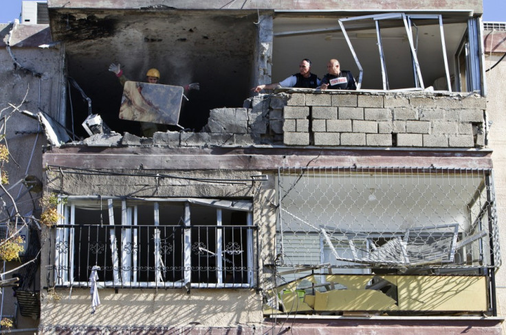 An Israeli soldier throws a blood-stained table out of a building damaged by a rocket, fired from Gaza,