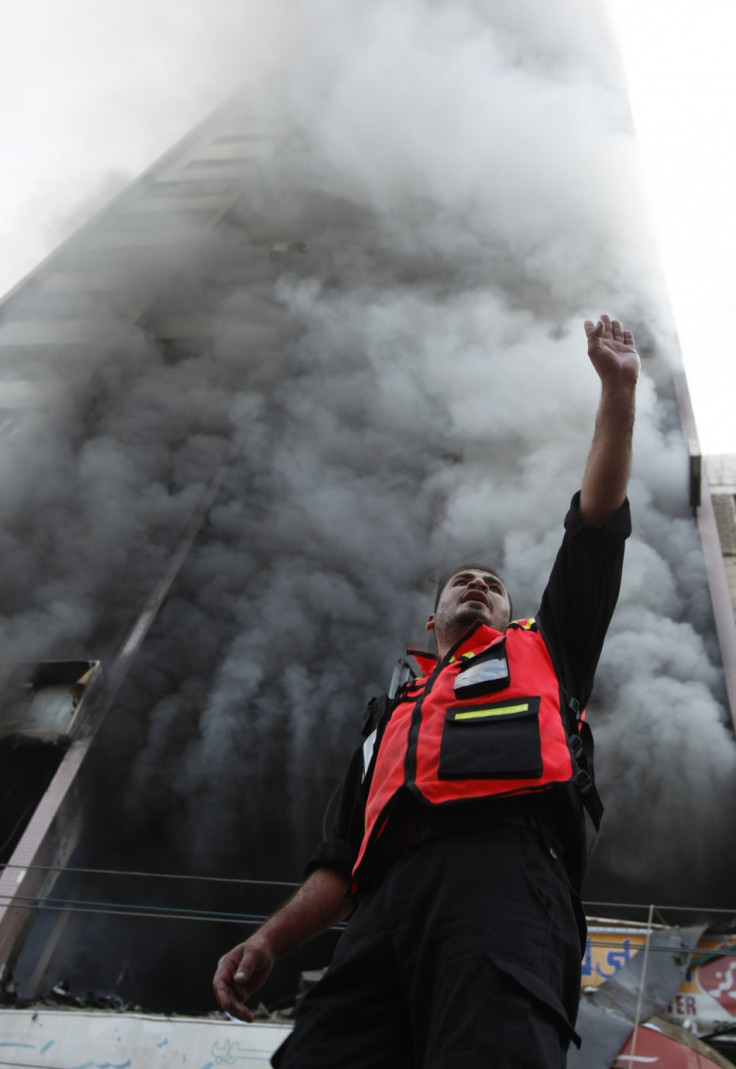 A Palestinian firefighter gestures as smoke rises out of a building that also houses international media offices,