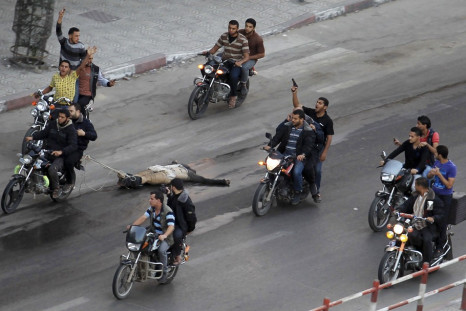 Palestinian gunmen ride motorcycles as they drag the body of a man, who was suspected of working for Israel,