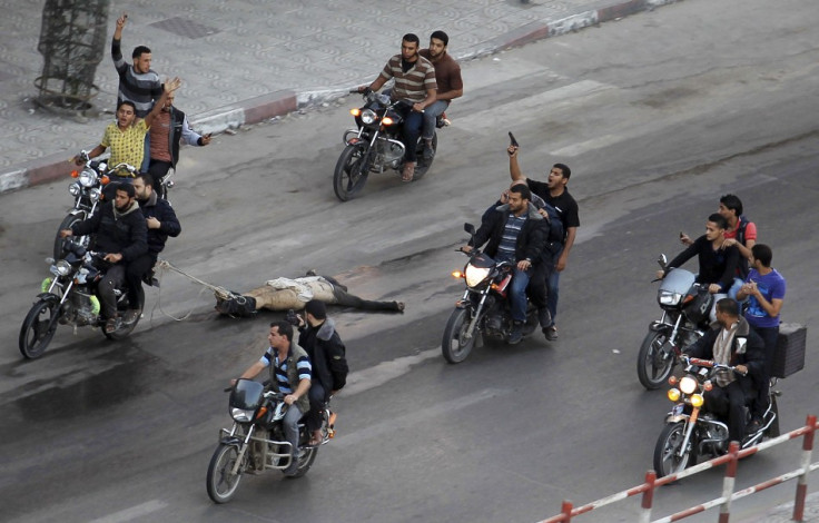 Palestinian gunmen ride motorcycles as they drag the body of a man, who was suspected of working for Israel,