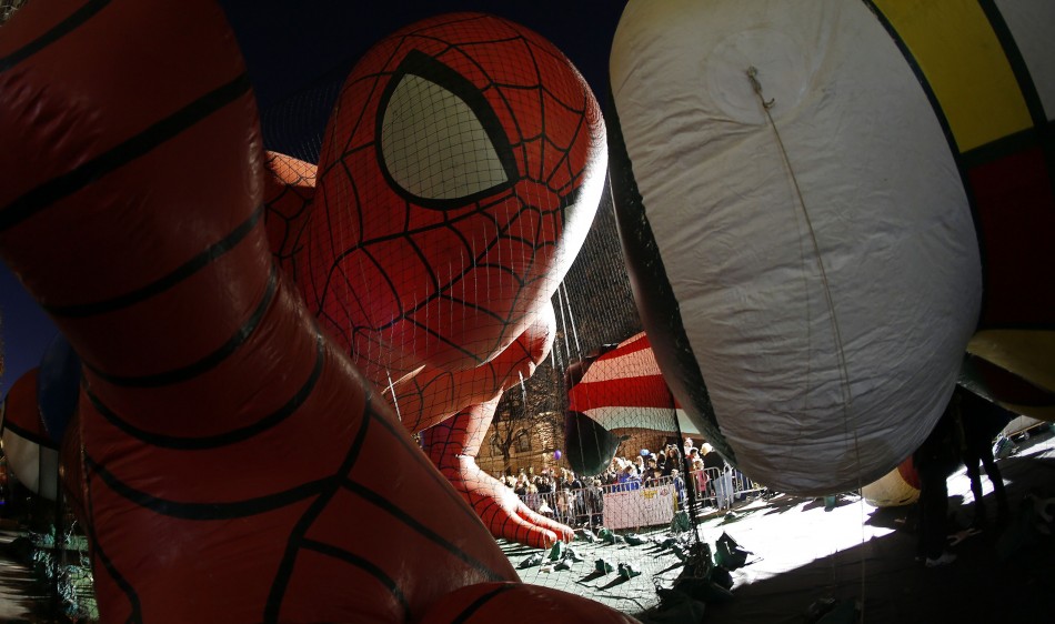 People viewing floats, pass by a balloon in the shape of Spider Man ahead of the Macys Thanksgiving Parade in New York