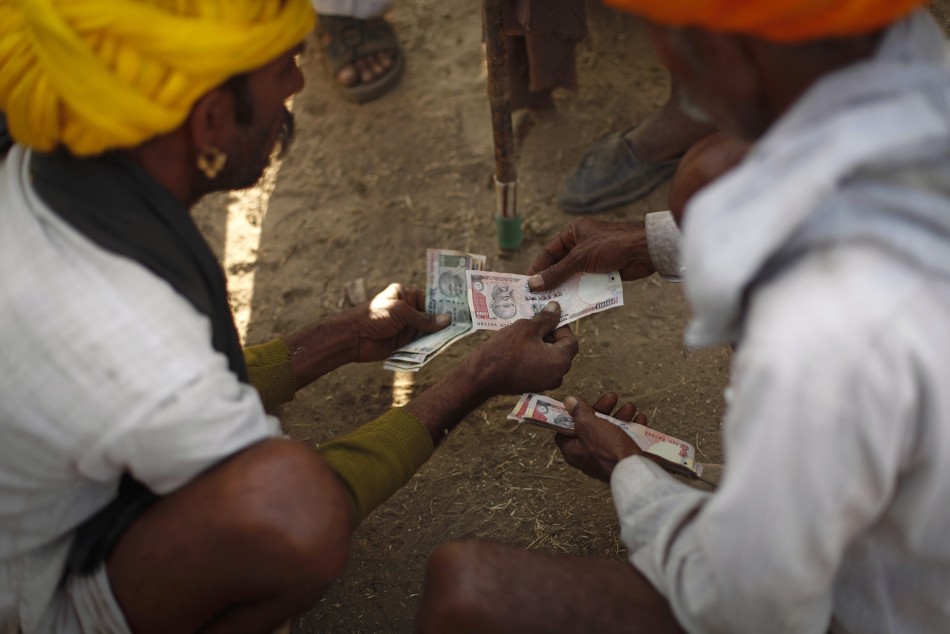 Camel herders count money at Pushkar Fair in the desert Indian state of Rajasthan