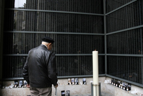 A man stands in front of a wall bearing the names of victims during the Holocaust memorial day