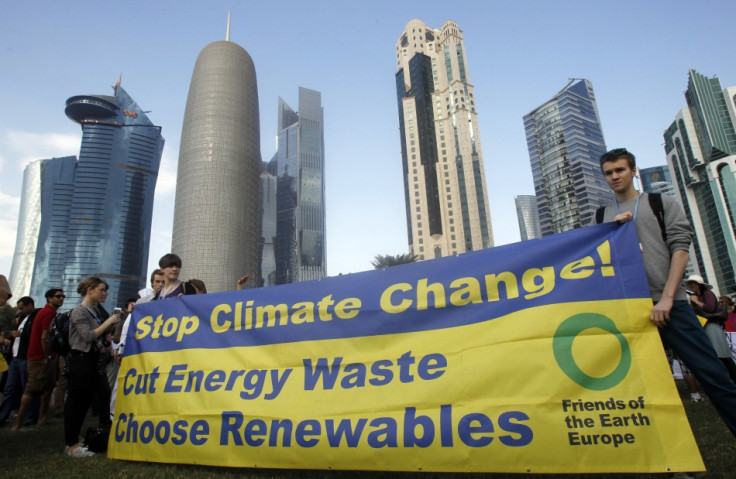 Activists stand with a banner before a march to demand action to address climate change in Doha