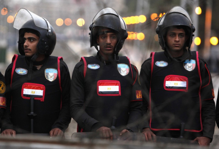 Egypt's riot police stand behind a barbed wire fence closing off the road before a demonstration