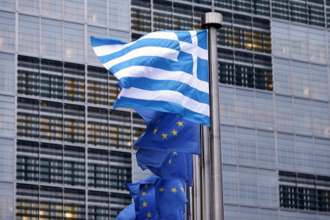 A Greek national flag flies next to EU flags