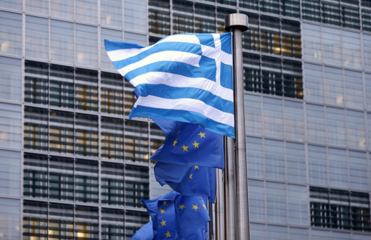 A Greek national flag flies next to EU flags