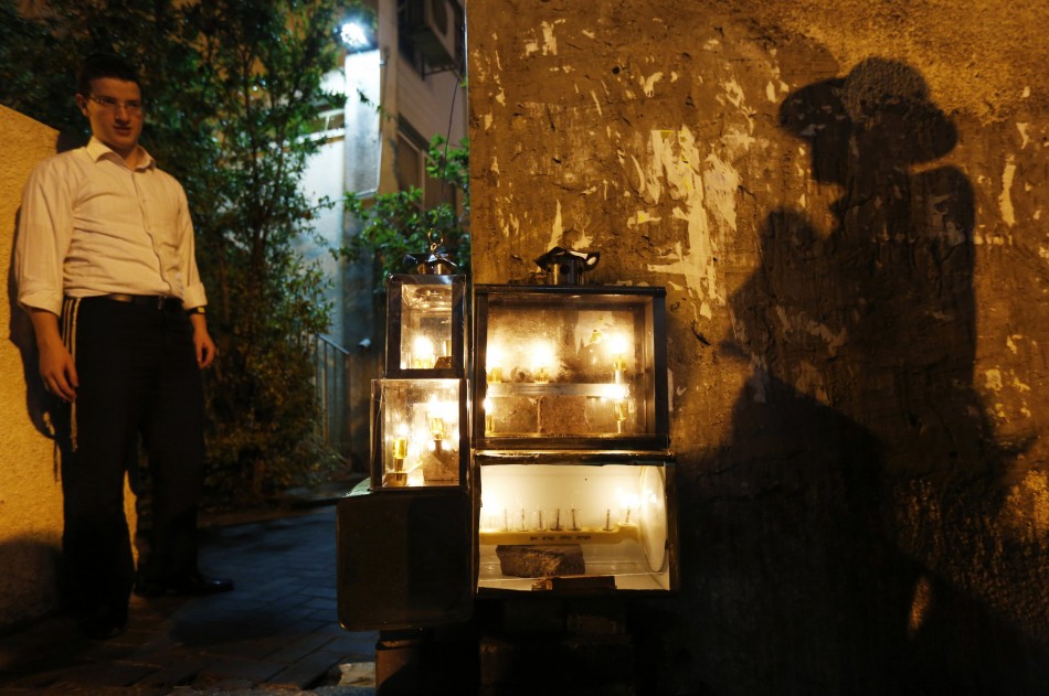 An ultra-Orthodox Jewish man casts a shadow near candles lit for Hanukkah in Ashdod