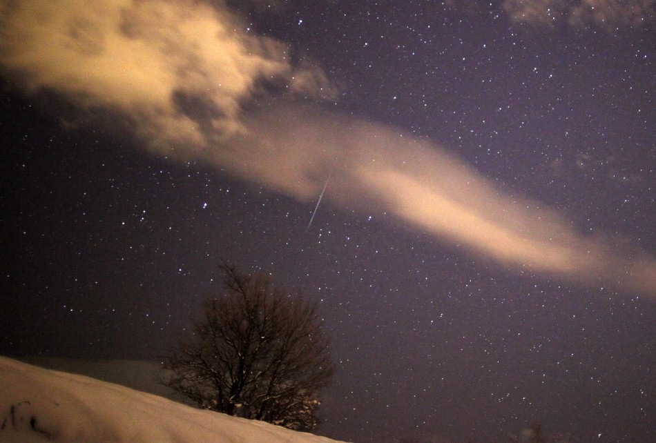 A meteor streaks past stars in the night sky over the village of Pesevici